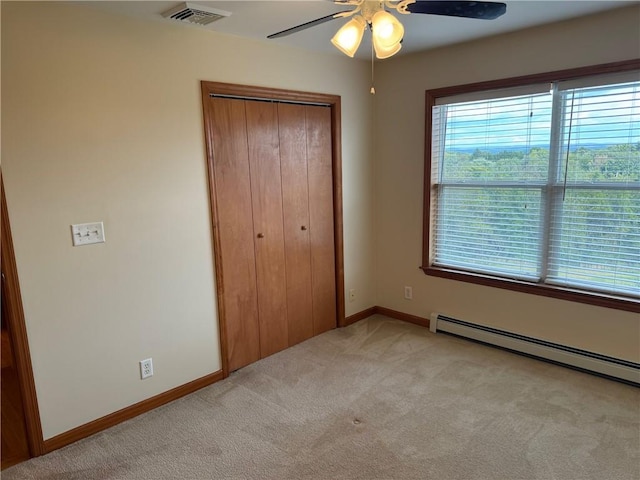 unfurnished bedroom featuring a baseboard radiator, a closet, light colored carpet, and ceiling fan