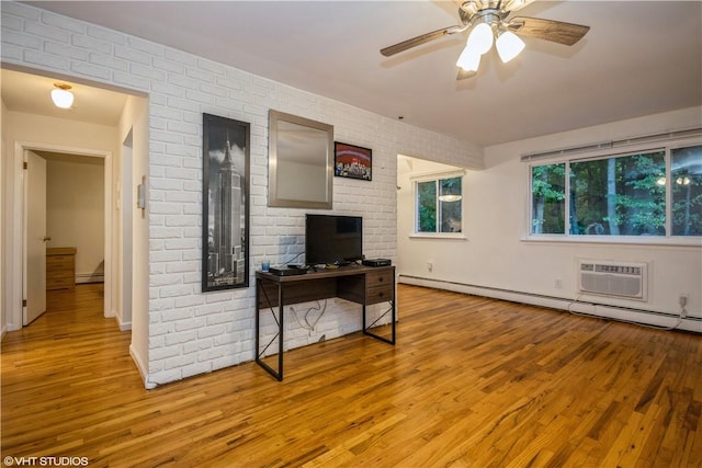 living room featuring an AC wall unit, ceiling fan, baseboard heating, light hardwood / wood-style floors, and brick wall