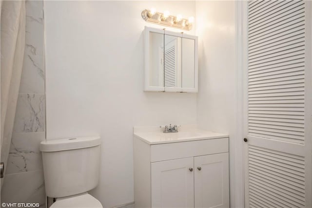 bathroom featuring vanity, toilet, and tile walls