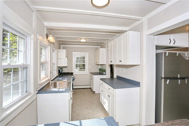 kitchen with stainless steel appliances, baseboard heating, sink, beamed ceiling, and white cabinets