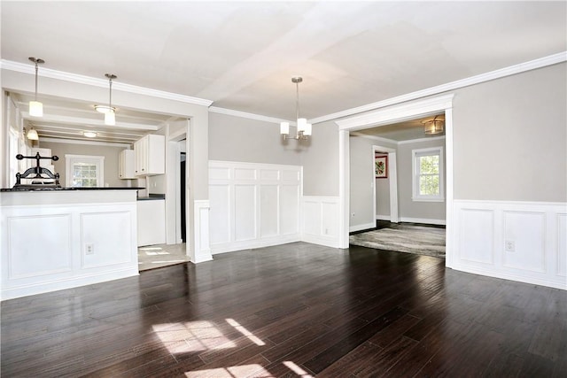 unfurnished living room featuring dark hardwood / wood-style flooring, crown molding, and a notable chandelier