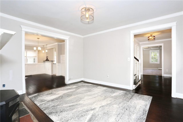 spare room with dark hardwood / wood-style floors, a baseboard radiator, ornamental molding, and a notable chandelier