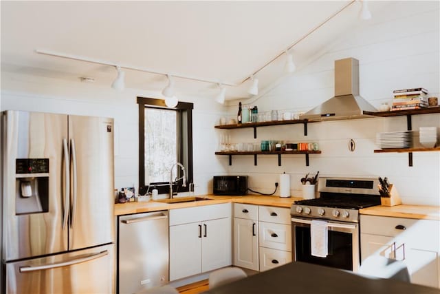 kitchen with white cabinets, sink, rail lighting, appliances with stainless steel finishes, and island range hood