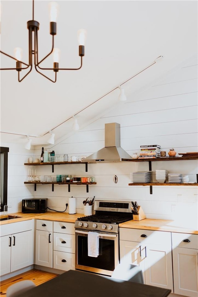 kitchen with island range hood, decorative light fixtures, a notable chandelier, white cabinets, and stainless steel range with gas stovetop