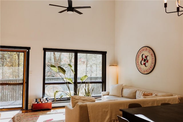 living room featuring baseboard heating, hardwood / wood-style floors, and ceiling fan with notable chandelier