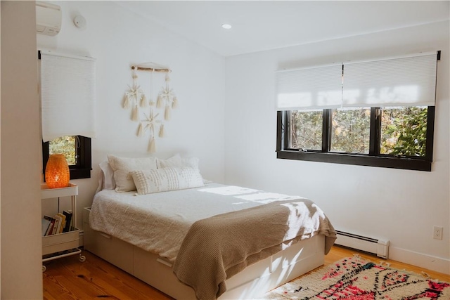 bedroom with wood-type flooring and a baseboard heating unit