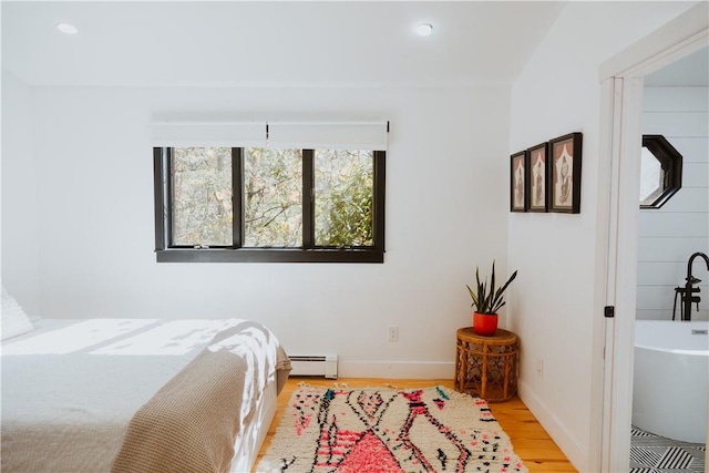 bedroom featuring light hardwood / wood-style floors and a baseboard heating unit