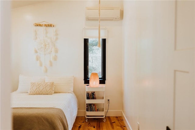 bedroom with a wall mounted AC and hardwood / wood-style floors