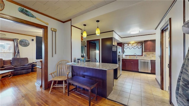 kitchen featuring appliances with stainless steel finishes, backsplash, a kitchen breakfast bar, pendant lighting, and light hardwood / wood-style flooring