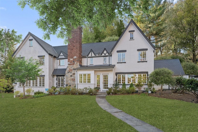 english style home featuring french doors and a front lawn