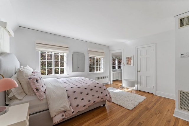 bedroom featuring radiator heating unit and light wood-type flooring