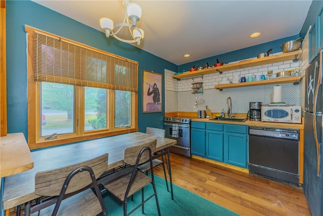 kitchen featuring sink, light hardwood / wood-style flooring, blue cabinetry, appliances with stainless steel finishes, and decorative light fixtures