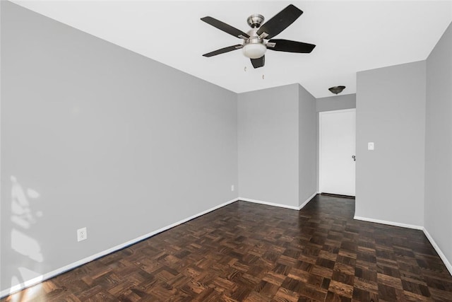 empty room featuring ceiling fan and dark parquet flooring