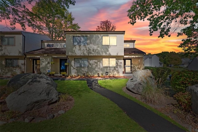 back house at dusk featuring a yard