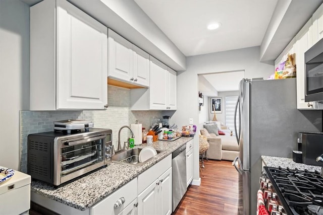 kitchen featuring light stone countertops, sink, dark hardwood / wood-style flooring, white cabinets, and appliances with stainless steel finishes