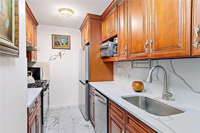 kitchen with light stone counters, sink, and appliances with stainless steel finishes