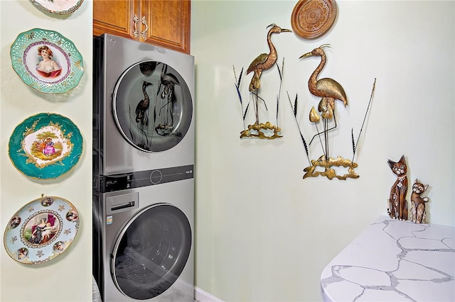 laundry room featuring cabinets and stacked washing maching and dryer