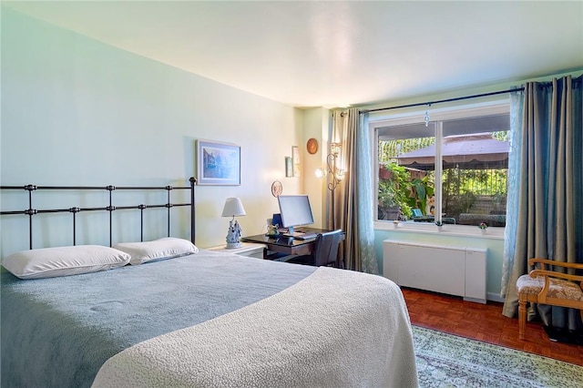 bedroom with dark parquet floors and radiator