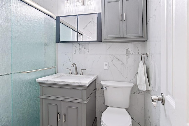 bathroom with vanity, toilet, and tile walls