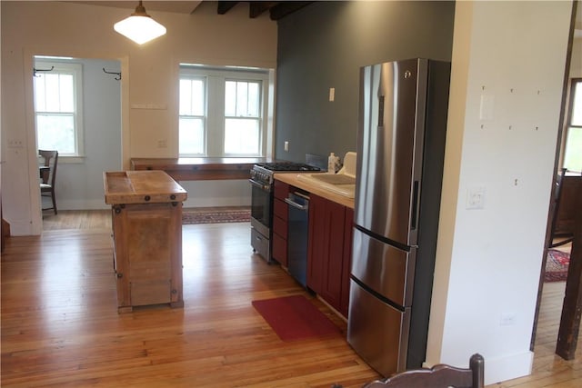 kitchen with decorative light fixtures, a healthy amount of sunlight, light hardwood / wood-style floors, and appliances with stainless steel finishes