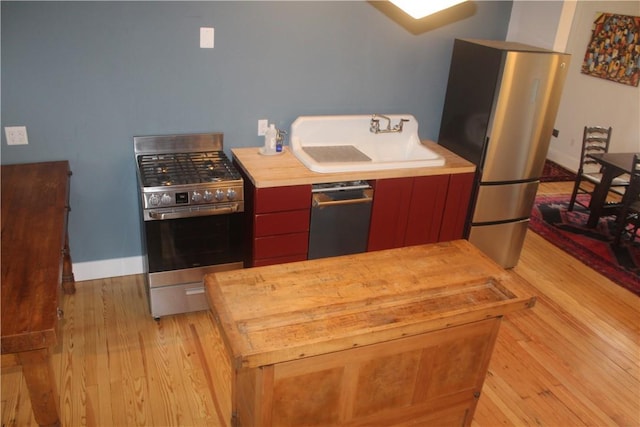 kitchen featuring butcher block counters, sink, light wood-type flooring, and stainless steel appliances