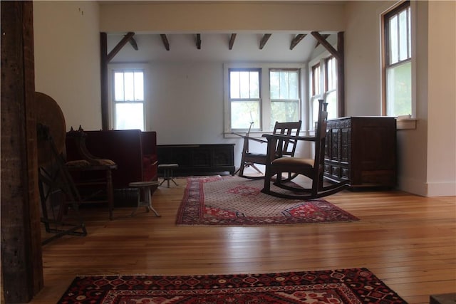 living area with lofted ceiling with beams and light hardwood / wood-style flooring