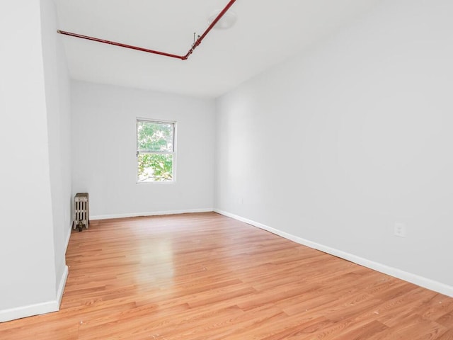 unfurnished room featuring radiator and light hardwood / wood-style floors