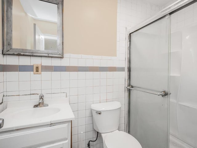 bathroom featuring vanity, toilet, a shower with shower door, and tile walls