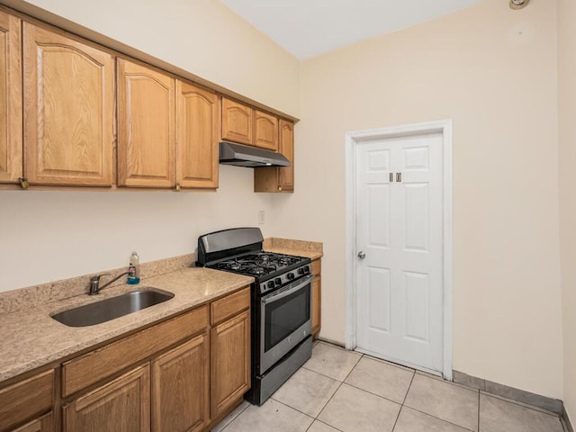 kitchen with light tile patterned flooring, sink, light stone countertops, and stainless steel gas range