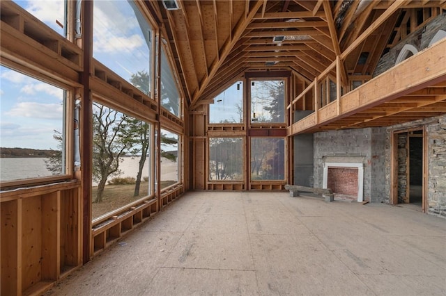 unfurnished sunroom featuring a fireplace, a water view, and vaulted ceiling