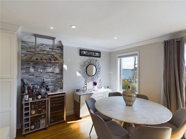 dining area with hardwood / wood-style floors, crown molding, beverage cooler, and bar