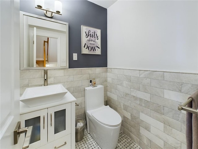 bathroom with toilet, vanity, tile patterned floors, and tile walls