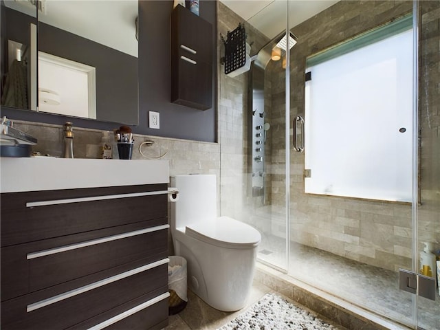 bathroom with tile patterned floors, walk in shower, vanity, tile walls, and toilet