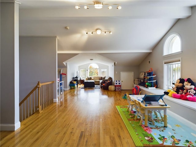 recreation room with wood-type flooring, lofted ceiling with beams, and a healthy amount of sunlight