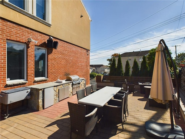 wooden terrace with an outdoor kitchen, a patio area, and grilling area