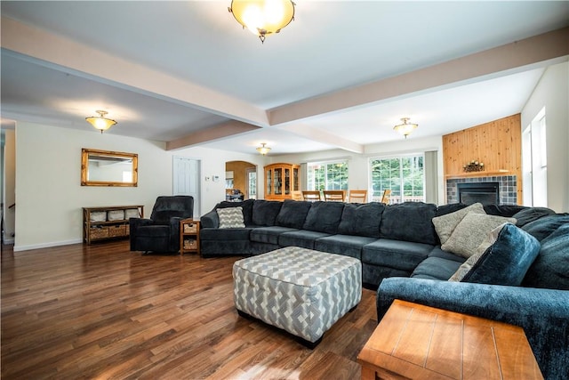 living room with beamed ceiling, dark hardwood / wood-style flooring, and a tile fireplace