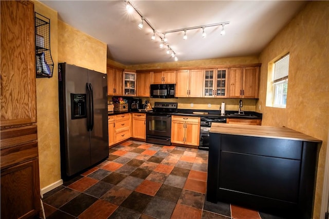 kitchen with wood counters, sink, track lighting, and black appliances