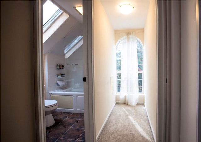 hallway with vaulted ceiling and dark colored carpet