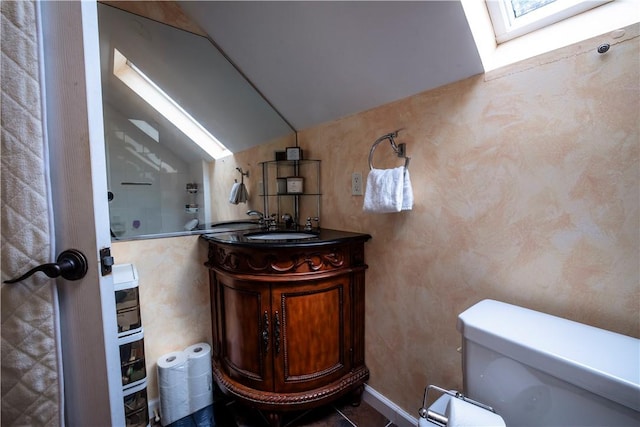 bathroom featuring vanity, toilet, and vaulted ceiling with skylight