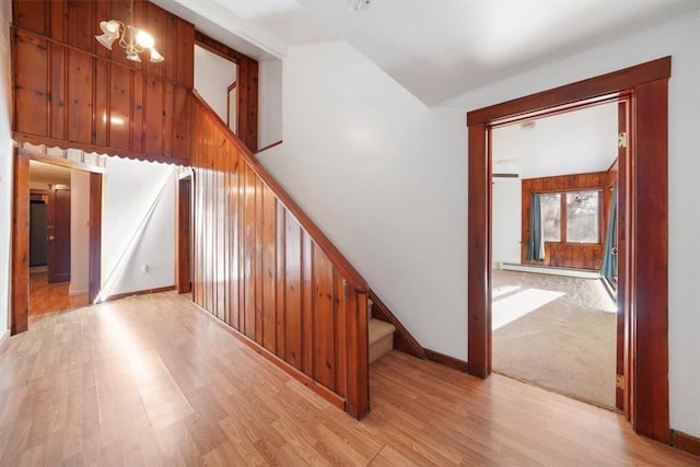 stairway featuring baseboard heating, wood-type flooring, vaulted ceiling, and an inviting chandelier