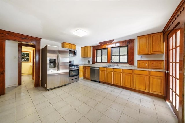 kitchen featuring sink, light tile patterned floors, baseboard heating, and appliances with stainless steel finishes