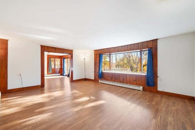 empty room featuring wood-type flooring and a baseboard heating unit