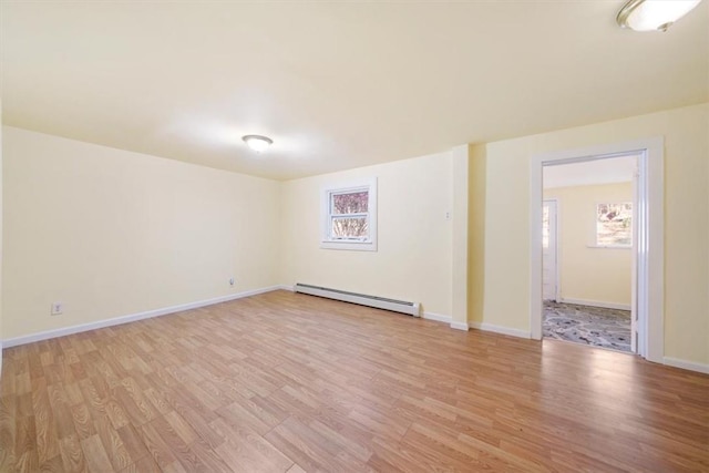 spare room featuring baseboard heating, light hardwood / wood-style flooring, and plenty of natural light