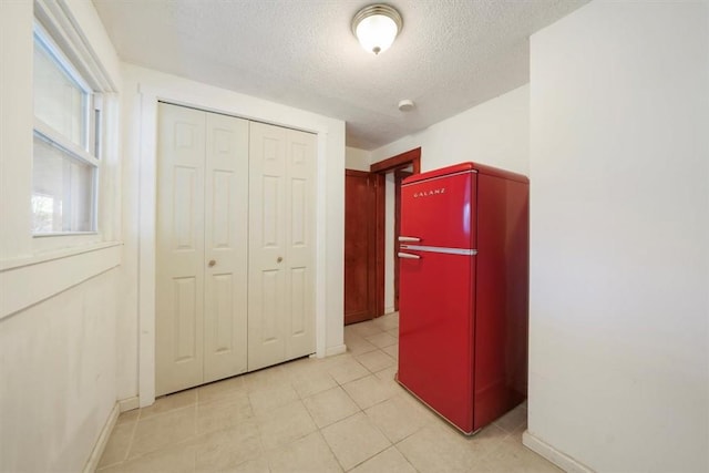 hall featuring light tile patterned floors and a textured ceiling