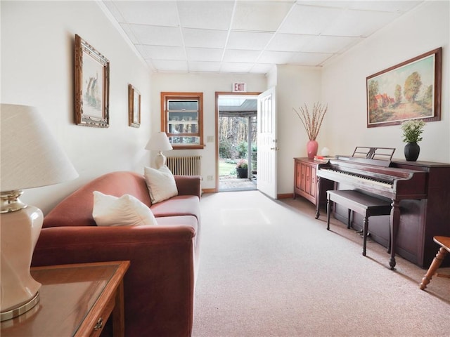 sitting room with radiator, a drop ceiling, and light colored carpet