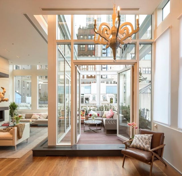 doorway to outside with a healthy amount of sunlight, wood-type flooring, and a notable chandelier