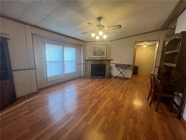 living room with a brick fireplace, a textured ceiling, vaulted ceiling, ceiling fan, and hardwood / wood-style floors