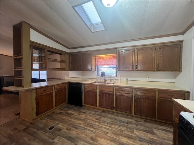 kitchen featuring sink, dark wood-type flooring, kitchen peninsula, lofted ceiling with skylight, and black appliances