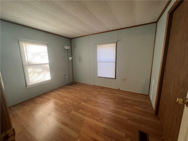 spare room featuring light hardwood / wood-style floors and a textured ceiling