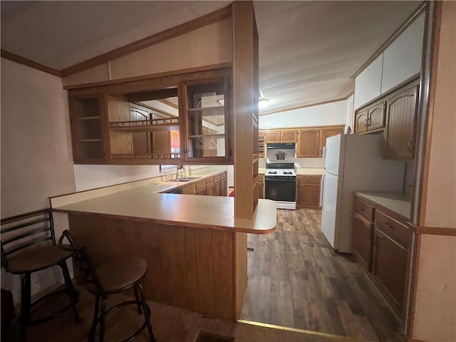 kitchen featuring kitchen peninsula, white appliances, vaulted ceiling, dark wood-type flooring, and a breakfast bar area